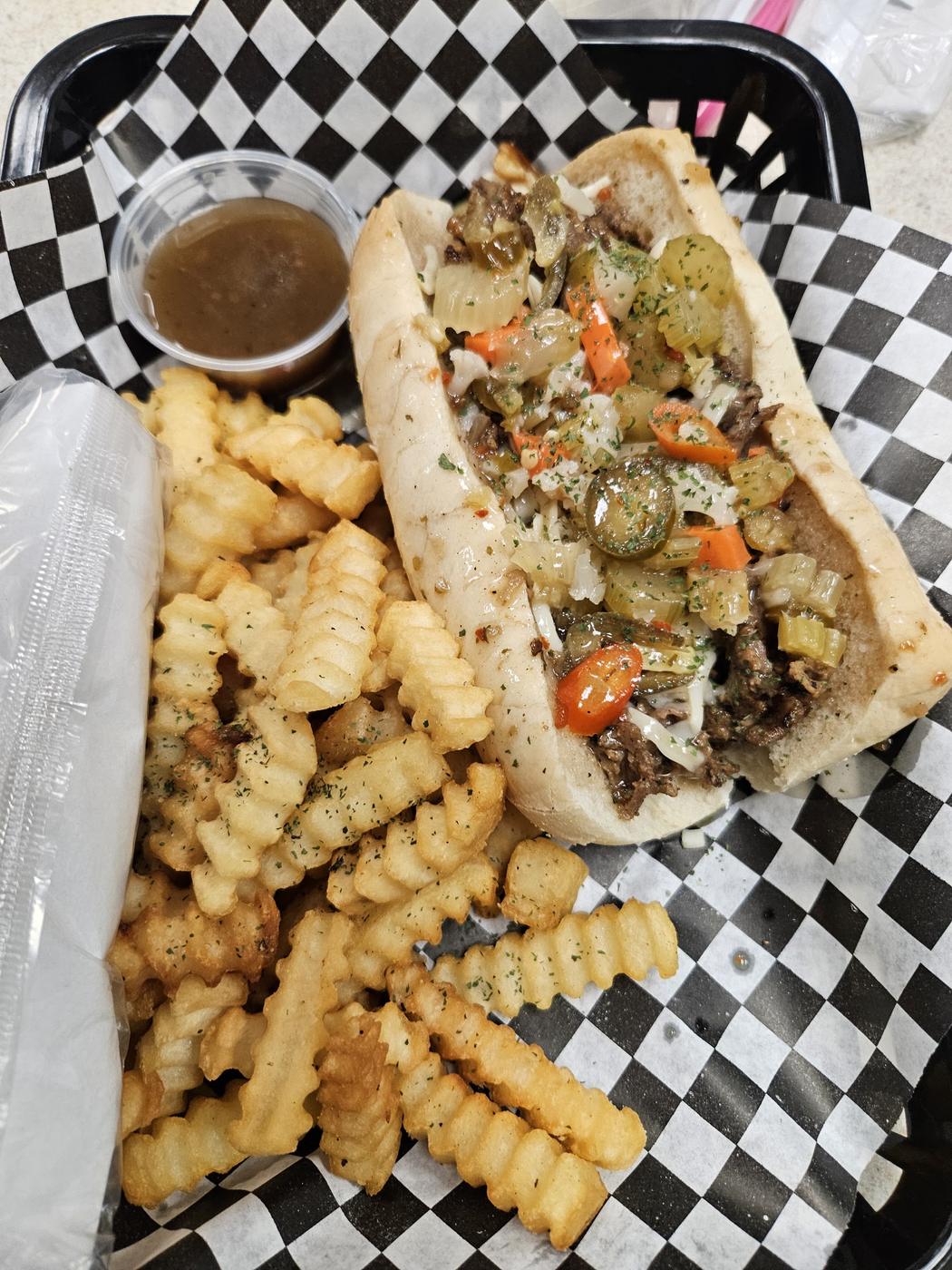 A loaded steak hoagie with peppers, served with crinkle fries